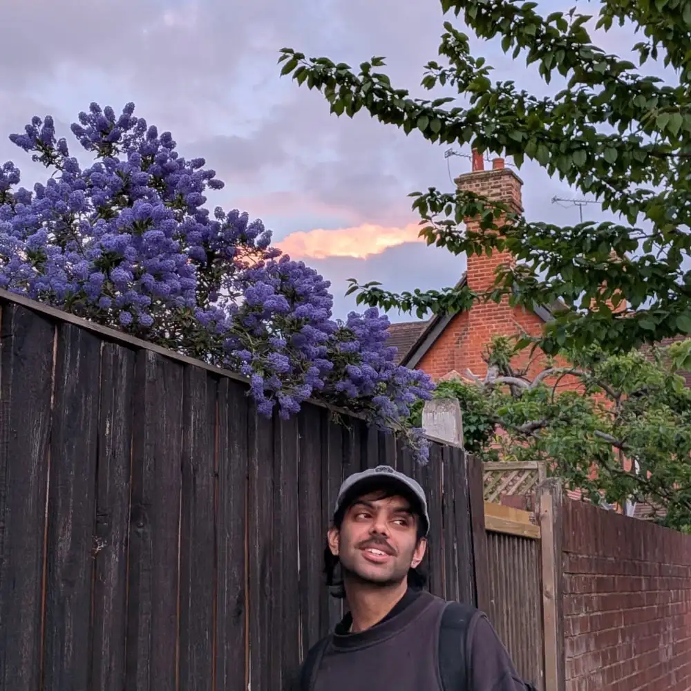 Anish Kumar posing under the blooming purple flowers