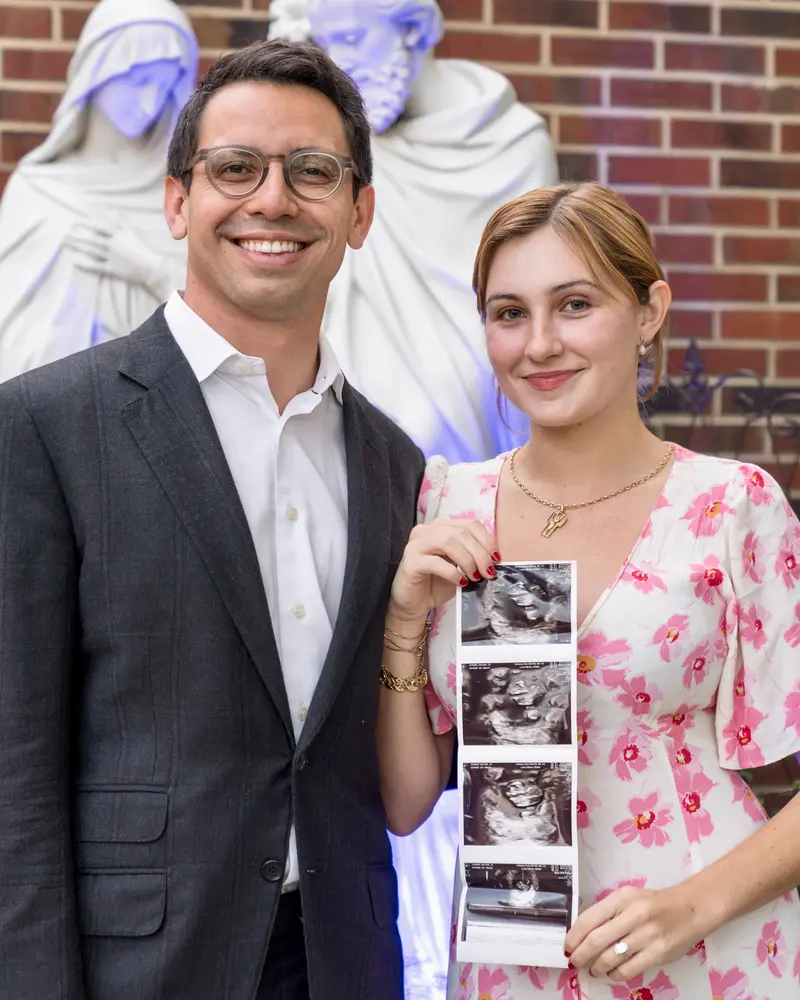 James Fishback and his wife Valeria Fishback posing together as she holds up ultrasound photos to announce that they are expecting their first child