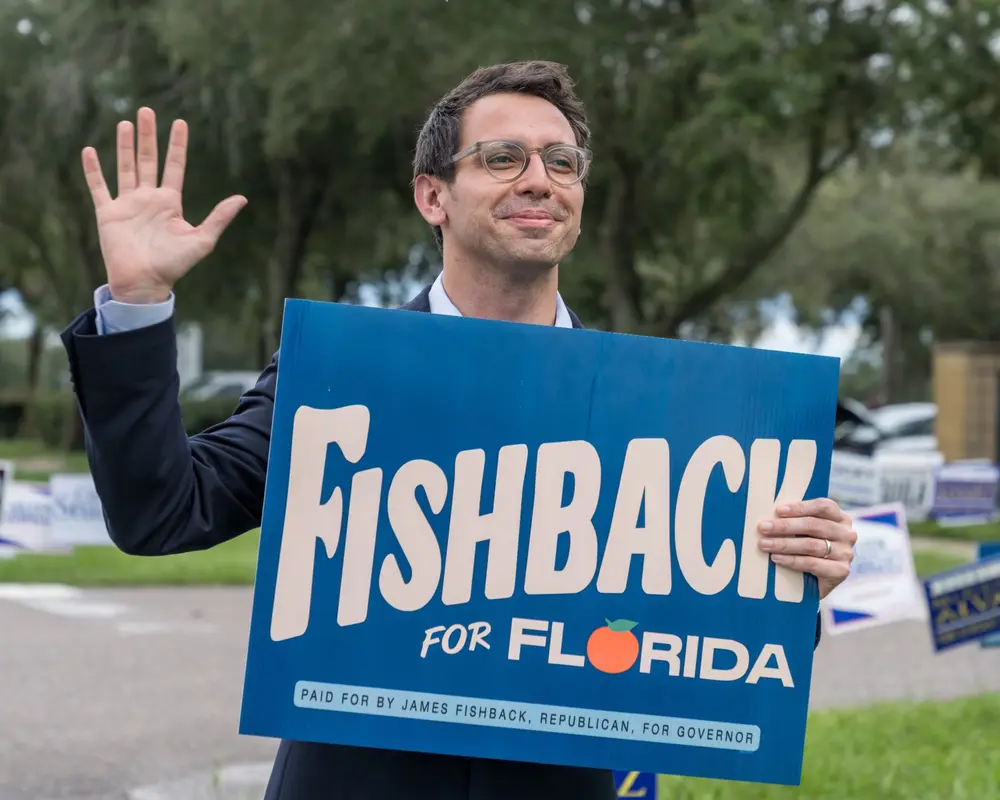 James Fishback holding a Fishback for Florida campaign sign while waving to voters